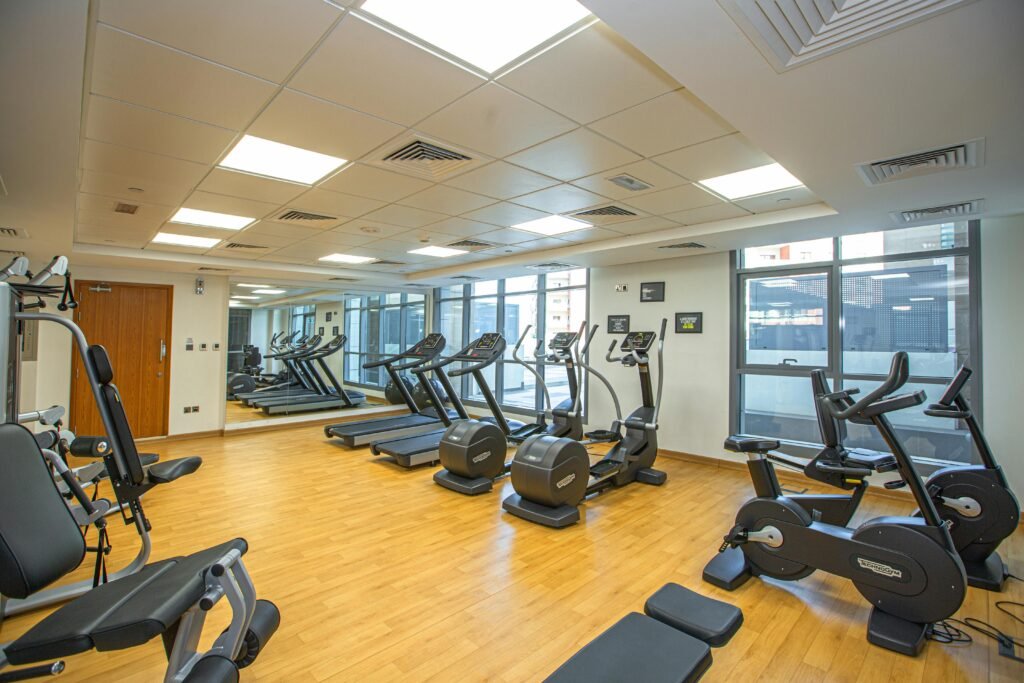 Spacious indoor gym with treadmills, stationary bikes, and exercise equipment on a wooden floor.